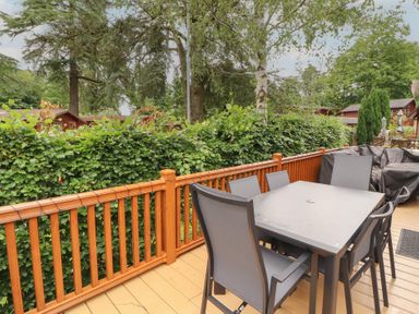 A table and chairs on a deck at Beech Grove Lodge, Glade 17, Fallbarrow Park near Bowness on Windermere