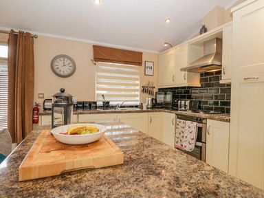 A kitchen with a fruit bowl on a cutting board and various appliances at Pheasant's Nest Kirkstone 11 Limefitt Park near Windermere