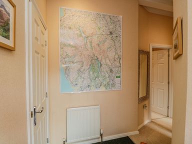 A hallway with a large map on the wall a radiator a mirror and two doors at Pheasant's Nest Kirkstone 11 Limefitt Park near Windermere