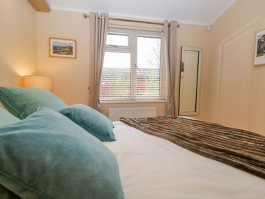 A bedroom with a bed a window with blinds and curtains a lamp and a mirror at Pheasant's Nest Kirkstone 11 Limefitt Park near Windermere