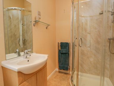 A bathroom with a sink, mirror, glass shelf, towel rack with towels, and a glass-enclosed shower at Pheasant's Nest Kirkstone 11 Limefitt Park near Windermere