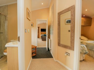 A hallway with a mirror on the wall a bathroom to the left a bedroom to the right and a living room straight ahead at Pheasant's Nest Kirkstone 11 Limefitt Park near Windermere
