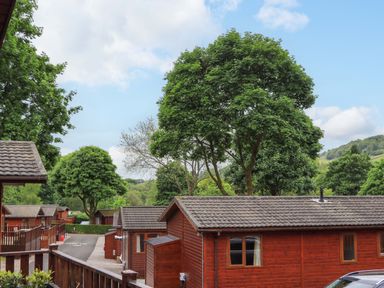 A view of wooden lodges and trees in a park setting at Pheasant's Nest Kirkstone 11 Limefitt Park near Windermere