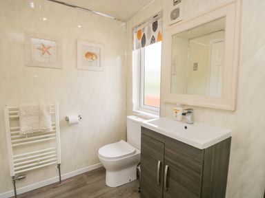A bathroom with a toilet a sink with a cabinet a towel rack and framed pictures at Ambleside Lodge Fellside 3 Limefitt Park near Windermere