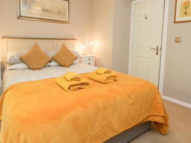 A bedroom with a bed covered with orange blankets and pillows near a white door at Ambleside Lodge Fellside 3 Limefitt Park near Windermere
