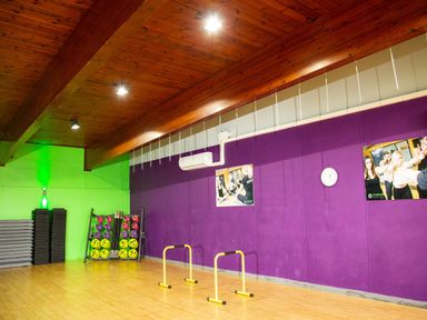 An empty fitness room with wooden floor purple and green walls exercise equipment and posters at Ambleside Lodge Fellside 3 Limefitt Park near Windermere