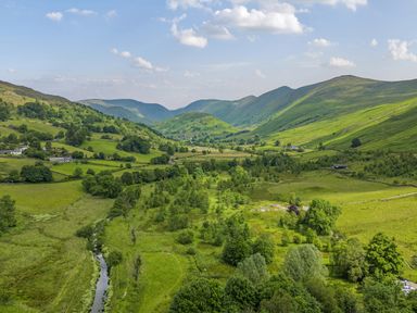 A green valley with a small river running through it and hills in the background at Ambleside Lodge Fellside 3 Limefitt Park near Windermere