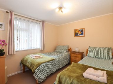 A bedroom with two single beds with green zigzag bedding and folded towels at Robin's Nest in Bowness 71 White Cross Bay near Windermere