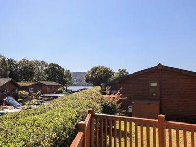 View of wooden cabins near a lake with trees and hills in the background at Robins Nest in Bowness 71 White Cross Bay near Windermere