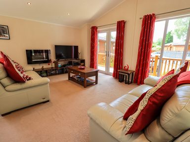 A living room with two sofas red curtains TV and coffee table at Robins Nest in Bowness 71 White Cross Bay near Windermere