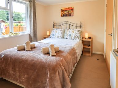 A bedroom with a double bed towels on the bed bedside tables and a window at Robins Nest Bowness 71 White Cross Bay near Windermere