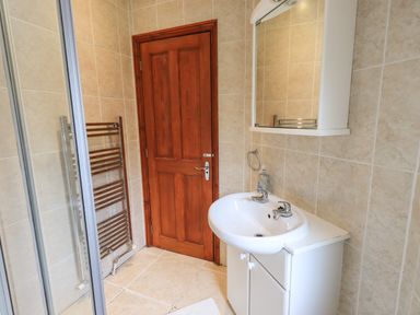 A bathroom with a wooden door a white sink with a cabinet and a mirror cabinet above with tiled walls at Thirlmere View Thirlmere 6 White Cross Bay near Windermere