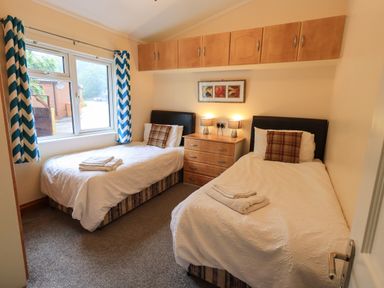 A bedroom with two single beds a chest of drawers lamps and a window at Thirlmere View Thirlmere 6 White Cross Bay near Windermere