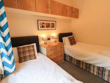 A bedroom with two single beds a chest of drawers and wall cabinets at Thirlmere View Thirlmere 6 White Cross Bay near Windermere