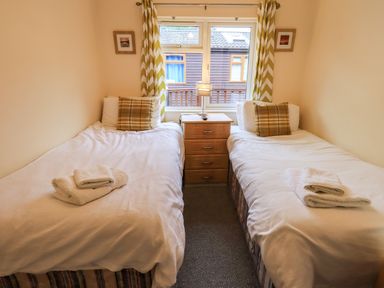 A bedroom with two single beds separated by a bedside table and a window at Thirlmere View in Thirlmere 6 White Cross Bay near Windermere