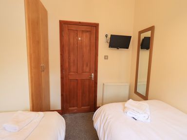 A bedroom with two beds a wooden door a wardrobe a wall-mounted tv and a mirror at Thirlmere View Thirlmere 6 White Cross Bay near Windermere