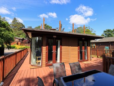 A wooden cabin with glass doors and a terrace with outdoor furniture at Thirlmere View Thirlmere 6 White Cross Bay near Windermere