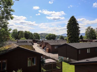 A group of wooden cabins with a street running between them surrounded by trees and hills at Thirlmere View Thirlmere 6 White Cross Bay near Windermere