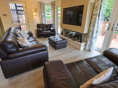 A living room with leather sofas a wall mounted television and glass doors at Thirlmere View Thirlmere 6 White Cross Bay near Windermere
