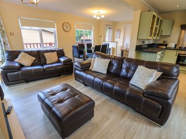 A living room with two leather sofas and an ottoman next to a dining area with a table and chairs at Thirlmere View Thirlmere 6 White Cross Bay near Windermere