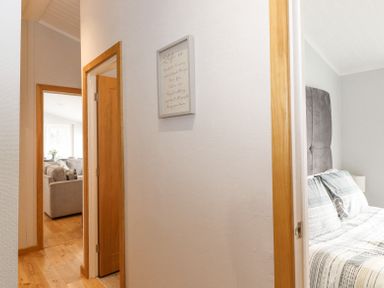 A hallway with wooden floors and doors leading to a living room and a bedroom at Lakes Lodge Keswick Court 3 White Cross Bay near Windermere