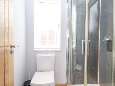 A bathroom with a toilet under a window next to a glass shower enclosure at Lakes Lodge in Keswick Court 3 White Cross Bay near Windermere