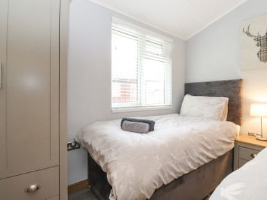 A bedroom with a bed, window blinds, bedside table with lamp, and wardrobe at Lakes Lodge Keswick Court 3 White Cross Bay near Windermere