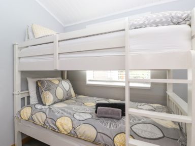 A bedroom with a white wooden bunk bed and patterned bedding at Lakes Lodge Keswick Court 3 White Cross Bay near Windermere