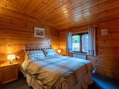 A bedroom with a double bed and wooden walls at Glaramara Number 7 Burnside Park near Keswick