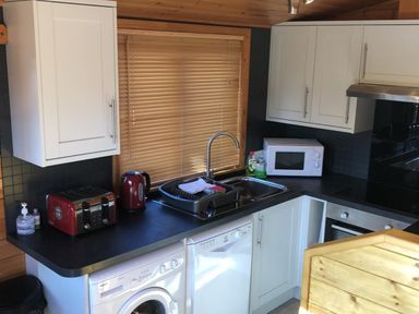A kitchen with a sink microwave red toaster and kettle washing machine at Glaramara Number 7 Burnside Park near Keswick