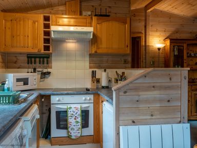 A kitchen with wooden cabinets a white oven a microwave and kitchen utensils at Rivendell Burnside Park Number 14 Burnside Park near Keswick