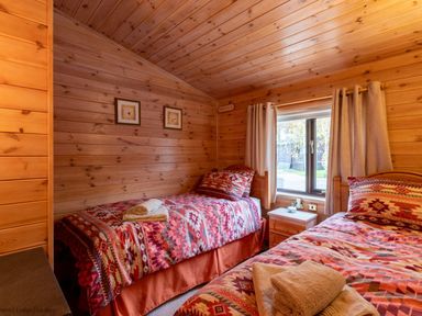 A bedroom with two single beds with patterned bedding and wooden walls at Burr Ghyll Number 27 Burnside Park near Keswick