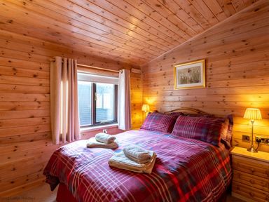 A bedroom with a double bed with checkered bedding and towels on the bed at Burr Ghyll Number 27 Burnside Park near Keswick