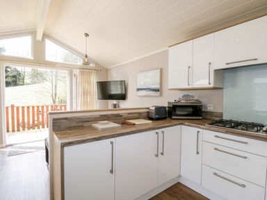 A kitchen with white cabinets and wooden countertops with a toaster and microwave at Troutbeck Lodge in Beckside 6 Limefitt Park near Windermere