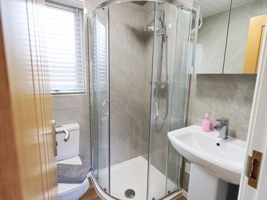 A bathroom with a shower enclosure toilet sink and a window at Troutbeck Lodge Beckside 6 Limefitt Park near Windermere