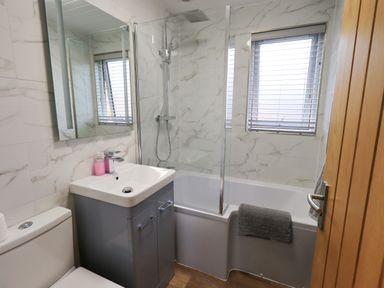 A bathroom with a toilet sink with cabinet bathtub shower and window blinds at Troutbeck Lodge in Beckside 6 Limefitt Park near Windermere