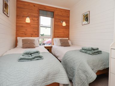 A bedroom with two single beds with blue bedspreads and towels on top at Ramblers Rest Lodge Pinewood 22 Limefitt Park near Windermere
