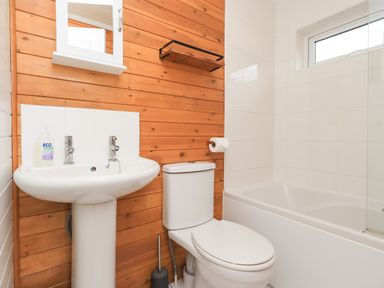 A bathroom with a sink toilet bathtub and wooden paneling on one wall at Ramblers Rest Lodge Pinewood 22 Limefitt Park near Windermere