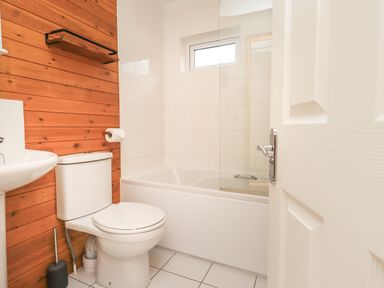 A bathroom with a toilet sink and bathtub against a wooden and tiled wall at Ramblers Rest Lodge Pinewood 22 Limefitt Park near Windermere