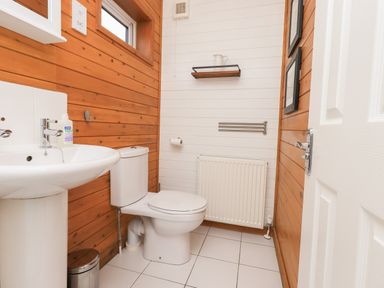 A bathroom with a sink and toilet with wooden panel walls at Ramblers Rest Lodge Pinewood 22 Limefitt Park near Windermere