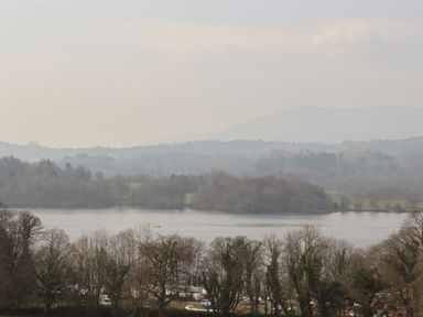 A lake with trees on the shore and hills in the background at Ramblers Rest Lodge Pinewood 22 Limefitt Park near Windermere