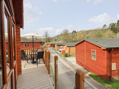 A balcony with a table umbrella and chairs at Ramblers Rest Lodge in Pinewood 22 Limefitt Park near Windermere
