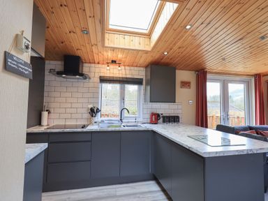 A kitchen with grey cabinets white tiled walls and a skylight at Striding Edge Lodge Ullswater 9 Limefitt Park near Windermere