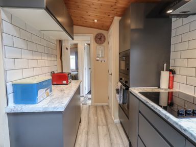A galley kitchen with grey cabinets and marble countertops at Striding Edge Lodge Ullswater 9 Limefitt Park near Windermere