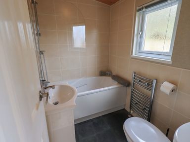 A bathroom with a bathtub a sink a toilet a towel rack and a window at Striding Edge Lodge Ullswater 9 Limefitt Park near Windermere