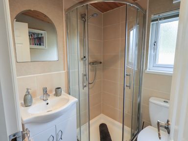 A bathroom with a glass shower enclosure a white sink with soap dispenser and cup a toilet and a window at Striding Edge Lodge Ullswater 9 Limefitt Park near Windermere