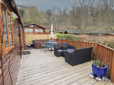 A wooden deck with outdoor seating and a table with an umbrella at Striding Edge Lodge Ullswater 9 Limefitt Park near Windermere