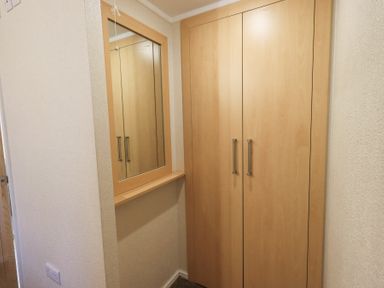 A corner with wooden wardrobe and a mirror on the wall at Horseshoe Lodge Wansfell 5 Limefitt Park near Windermere