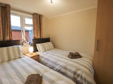 A bedroom with two single beds a nightstand and a window at Horseshoe Lodge in Wansfell 5 Limefitt Park near Windermere