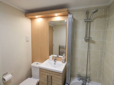 A bathroom with a toilet sink vanity and a bathtub with a shower at Horseshoe Lodge Wansfell 5 Limefitt Park near Windermere